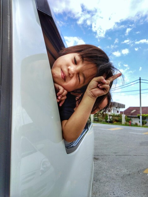 Speels meisje kijkt door het raam van de auto.