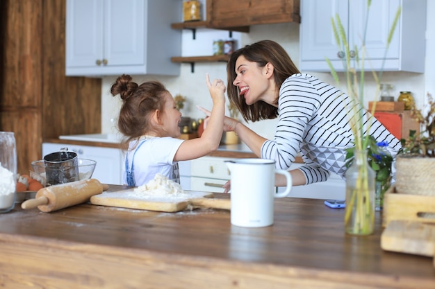 Speels meisje koken in de keuken met haar liefhebbende moeder.