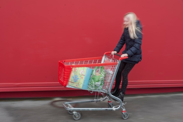 Foto speels meisje op winkelwagentje tegen de muur