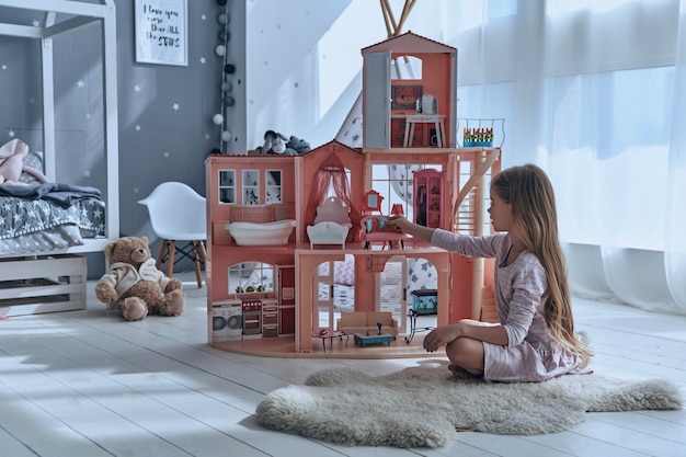 Speels voelen. Schattig klein meisje speelt met een poppenhuis terwijl