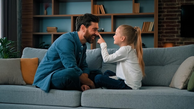 Speelse blanke jonge familie papa en kleine dochter zitten comfortabel op de bank en houden van schattig