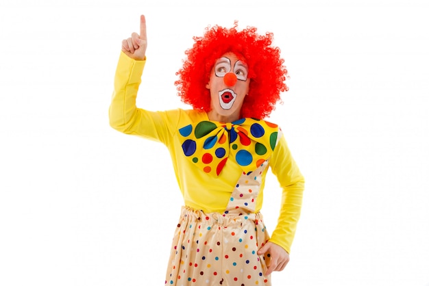 Speelse clown in rode pruik die naar boven wijst.