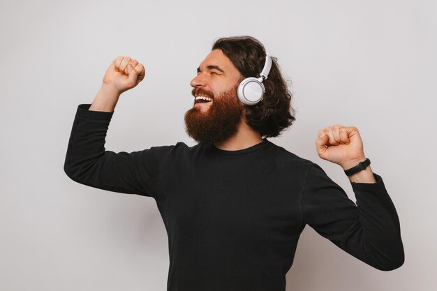 Speelse extatische man danst terwijl hij naar de muziek luistert in een koptelefoon