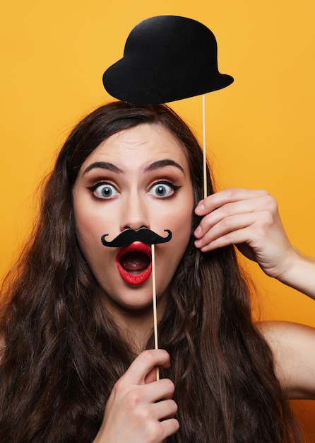 Foto speelse jonge vrouw klaar voor feest over gele achtergrond