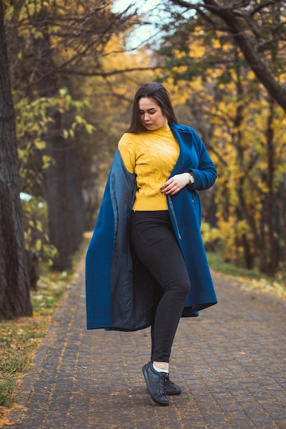 Speelse jonge vrouw met herfstbladeren in de hand en herfst gele esdoorn tuin achtergrond