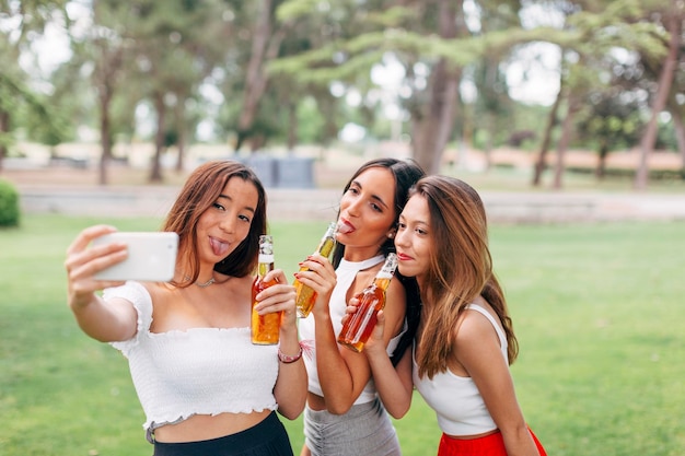 Speelse vrienden in een park bier drinken en een selfie maken