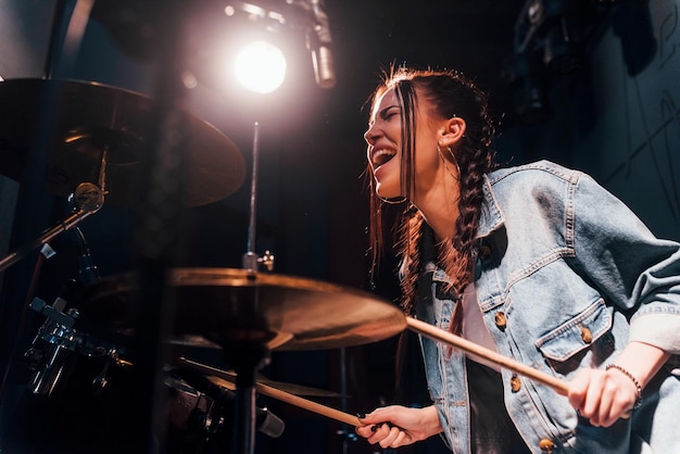 Speelt drums Jonge mooie vrouwelijke artiest repeteren in een opnamestudio