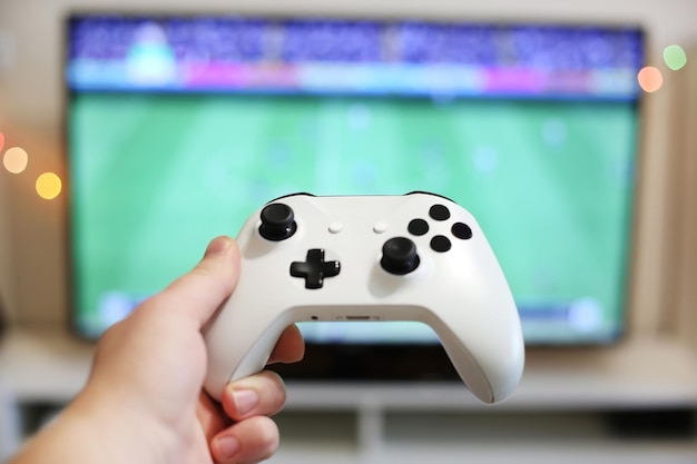 Speelt voetbal op tv, met witte gamepad vast