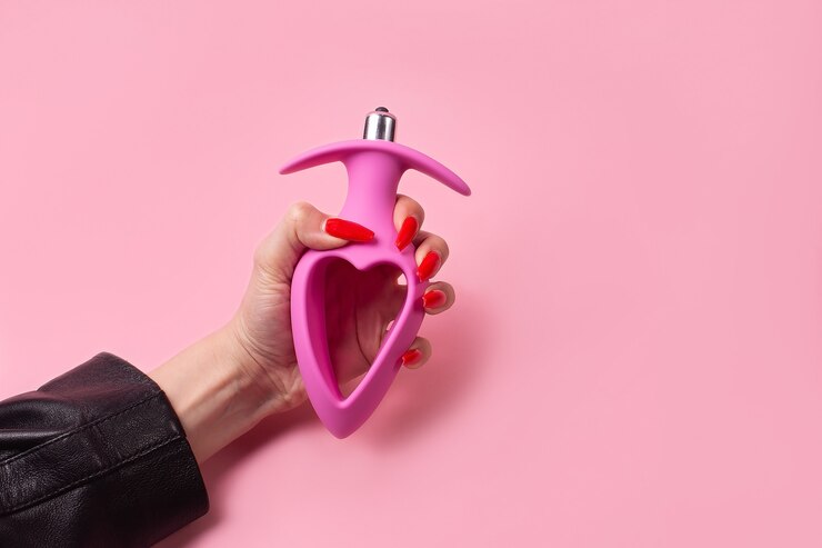 Speeltje voor volwassenen Dildo in de hand op een roze muur