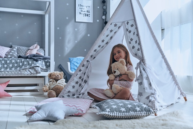 Spelen met speelgoed. Schattig klein meisje omhelst haar teddybeer en kijkt weg