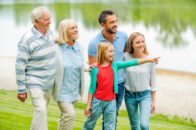 Spending quality time with family. Happy young family walking outdoors together while little girl pointing away and smiling