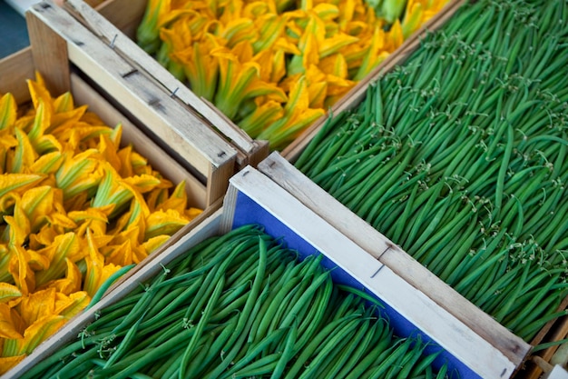 Sperziebonen en courgettebloemen op een marktkraam