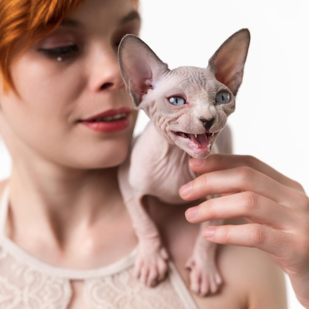 Sphynx haarloze kitten miauwen zittend op de schouder van roodharige jonge vrouw close-up weergave