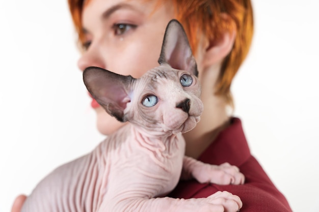 Sphynx kitten liggend op de schouder van roodharige vrouw Selectieve focus voorgrond ondiepe scherptediepte