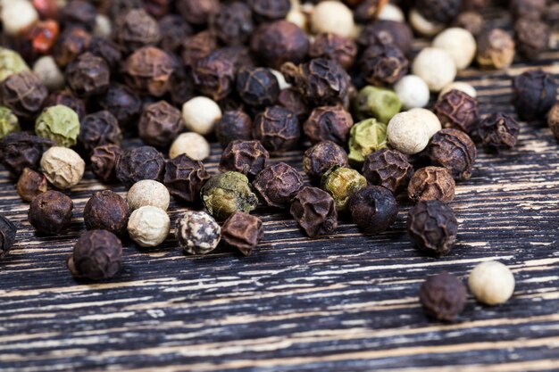 Spice black pepper scattered on an old wooden table in the kitchen, fragrant hot black pepper peas are used in cooking during the preparation of meat and other dishes