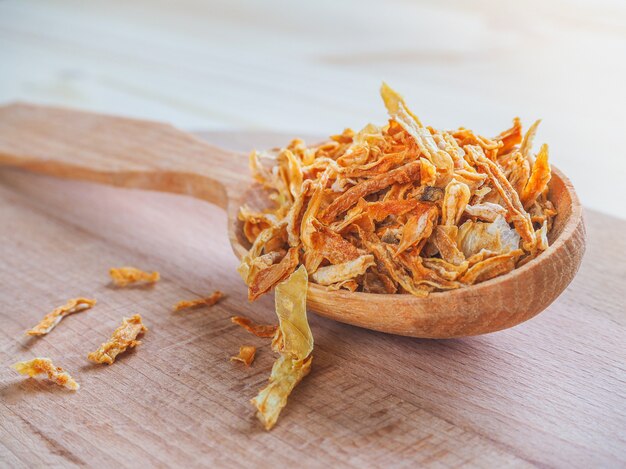 Spice dried onion and wooden spoon on a wooden table.