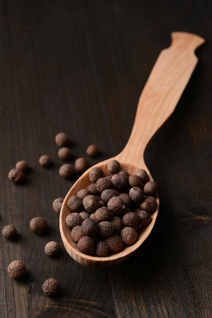 Photo spice pepper in spoon on wooden background