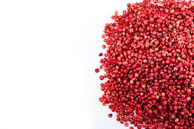 Spice. pink pepper. heap of pink peppercorns on a white\
background. spicy spice.