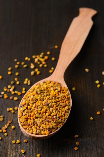 Spice pollen in spoon on wooden background