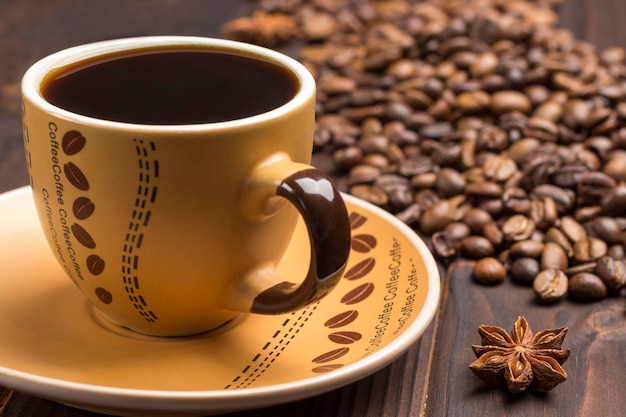 Spice star anise cup of coffee and saucer close up Grains of coffee on table Dark background