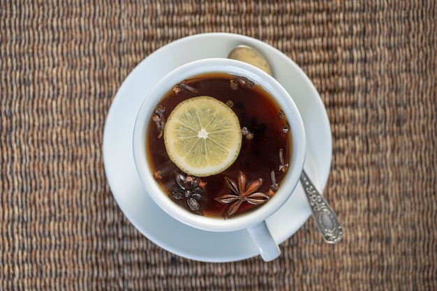 Foto tè speziato, composto da cannella, pepe nero, cardamomo, anice stellato, limone, chiodi di garofano e succo di mela caldo. primo piano, vista dall'alto. tè alla cannella. bere il tè