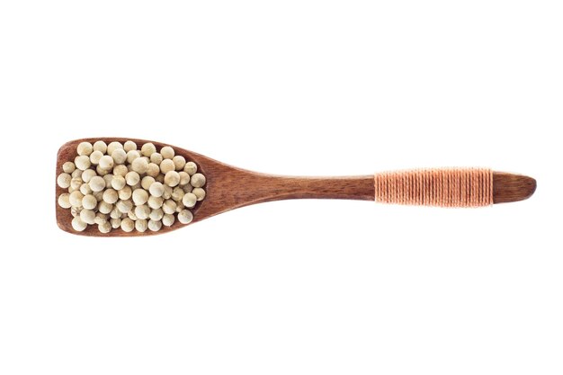 Spice white pepper in  wooden spoon isolated on a white background, top view