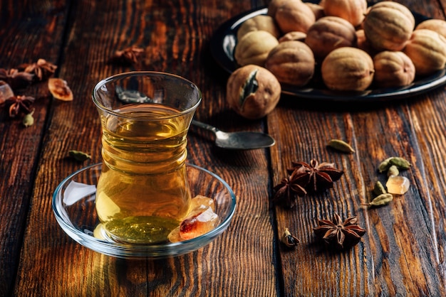 Spiced tea with star anise, cardamom and dried lime in armudu glass over wooden surface