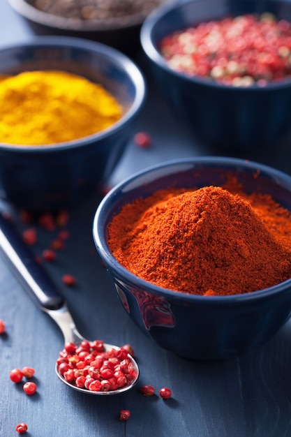 Spices in bowls: curry, pink and black pepper, paprika powder