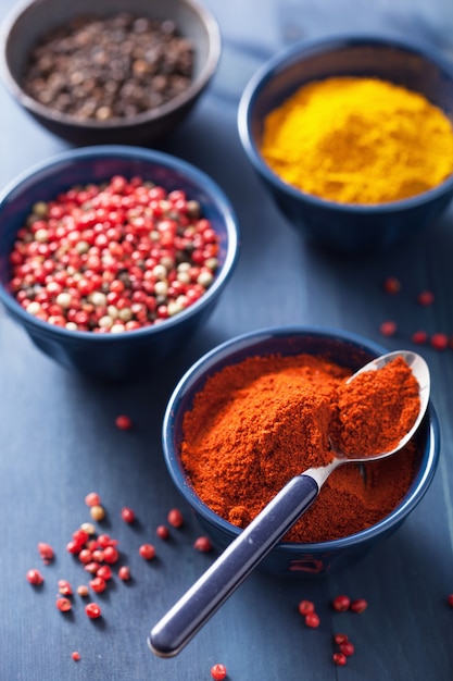 Spices in bowls: curry, pink black pepper, paprika powder