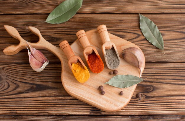 Spices for cooking Black pepper turmeric and red pepper with bay leaf and garlic on a wooden background