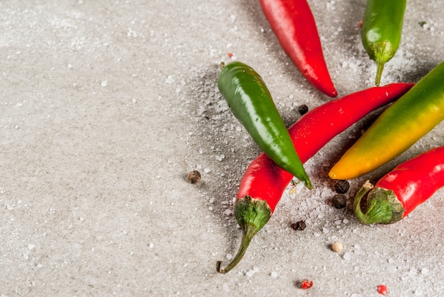 Foto spezie per cucinare. peperoncini piccanti rossi e verdi su pietra grigia,