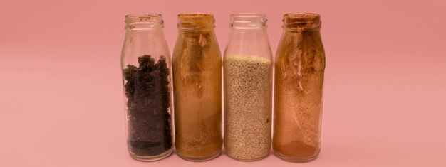 Spices in glass jars on a pink background