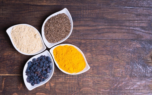 Spices and herbs in ceramic bowls on wooden background Traditional Indian food