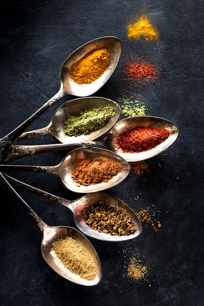 Photo spices and herbs spoons on a black background