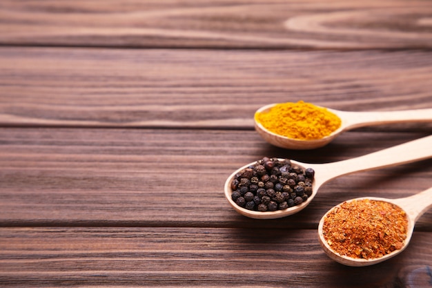 Spices mix in spoon on a brown wooden table.