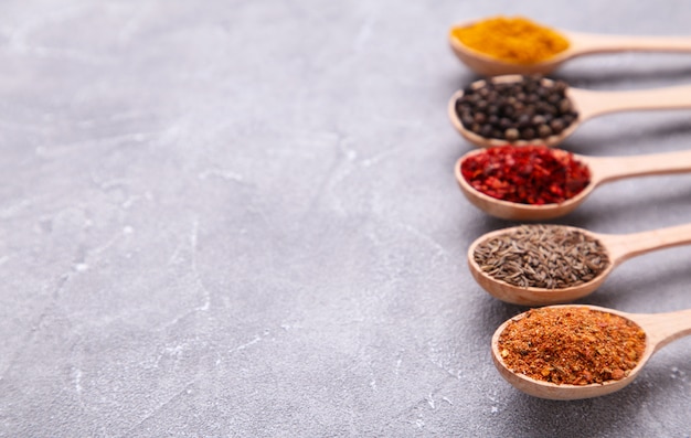 Spices mix on wooden spoons on a grey background. Top view