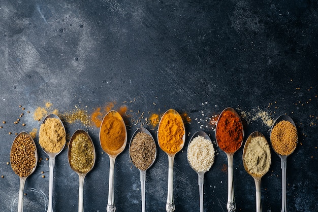 Spices in spoons background. Varieties of spices (turmeric, pepper, chili, coriander, cinnamon) and peppers for cooking. Culinary food concept.