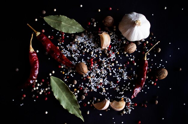spices white black and red peppers sea salt sprinkled garlic and chilli on a black background closeup