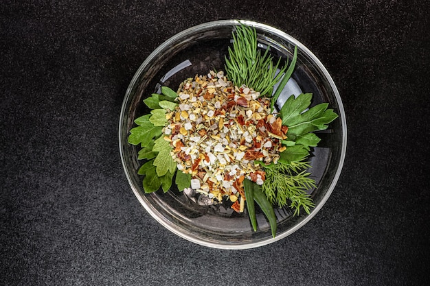 Spezie con erbe aromatiche fresche e sale marino grosso su un piatto. sfondo nero.