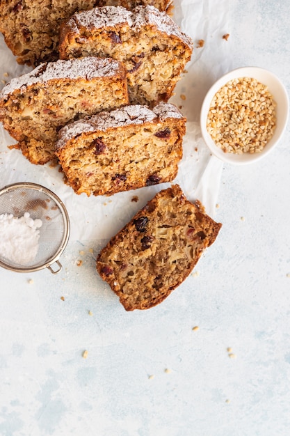 Spicy apple, nuts and dried cranberry loaf cake decorated with powdered sugar on a paper