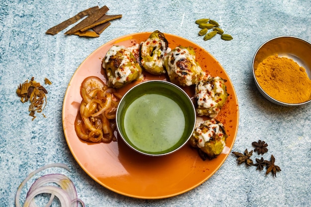 방글라데시 음식의 회색 배경에서 분리된 접시에 칠리 소스를 곁들인 매운 바베큐 치킨 레시미 티카 보티 케밥