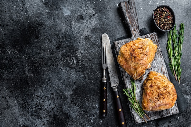 Spicy Bbq grilled chicken thighs on a wooden board with rosemary.   Top View.