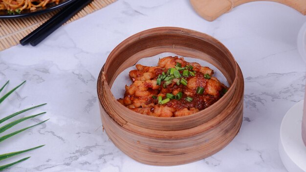 Spicy chicken feet in a wooden container with a ceramic background.