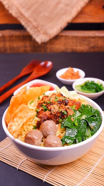 Spicy Chicken Noodles in a White Bowl on a wooden background and black base.