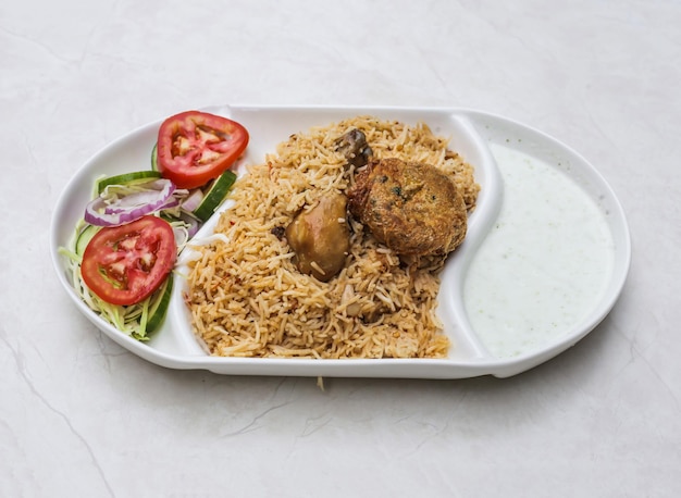 Spicy chicken pulao or biryani with raita and salad served in plate isolated on table top view of indian and pakistani spicy food