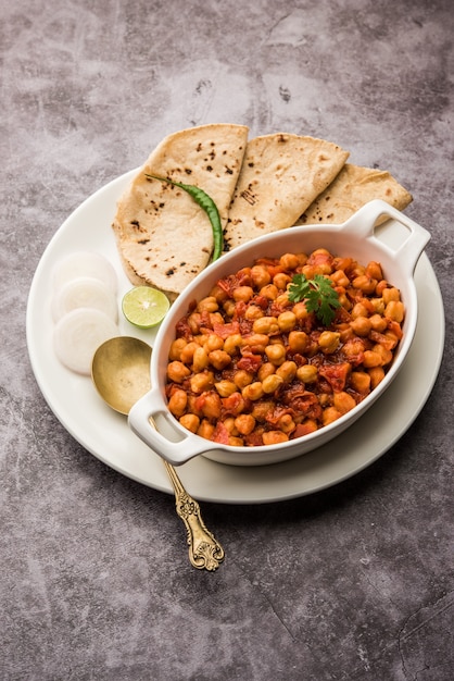 spicy chickpea curry, chana masala or choley in bowl with chapati and salad. traditional north indian dish.