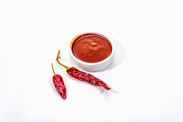Spicy chili sauce in bowl with hot chili peppers