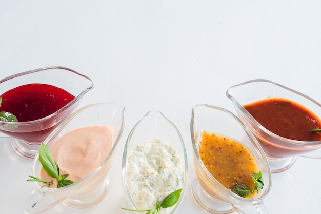 Spicy cooking set Assorted sauces in glass gravy boats Copy space on white background