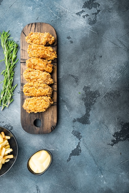 Spicy deep fried breaded chicken wings cuts on grey table, top view,.