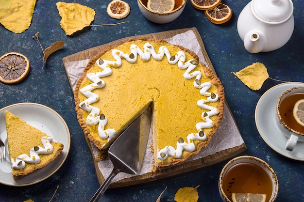 Spicy delicious round pumpkin pie decorated with white cream and pumpkin seeds